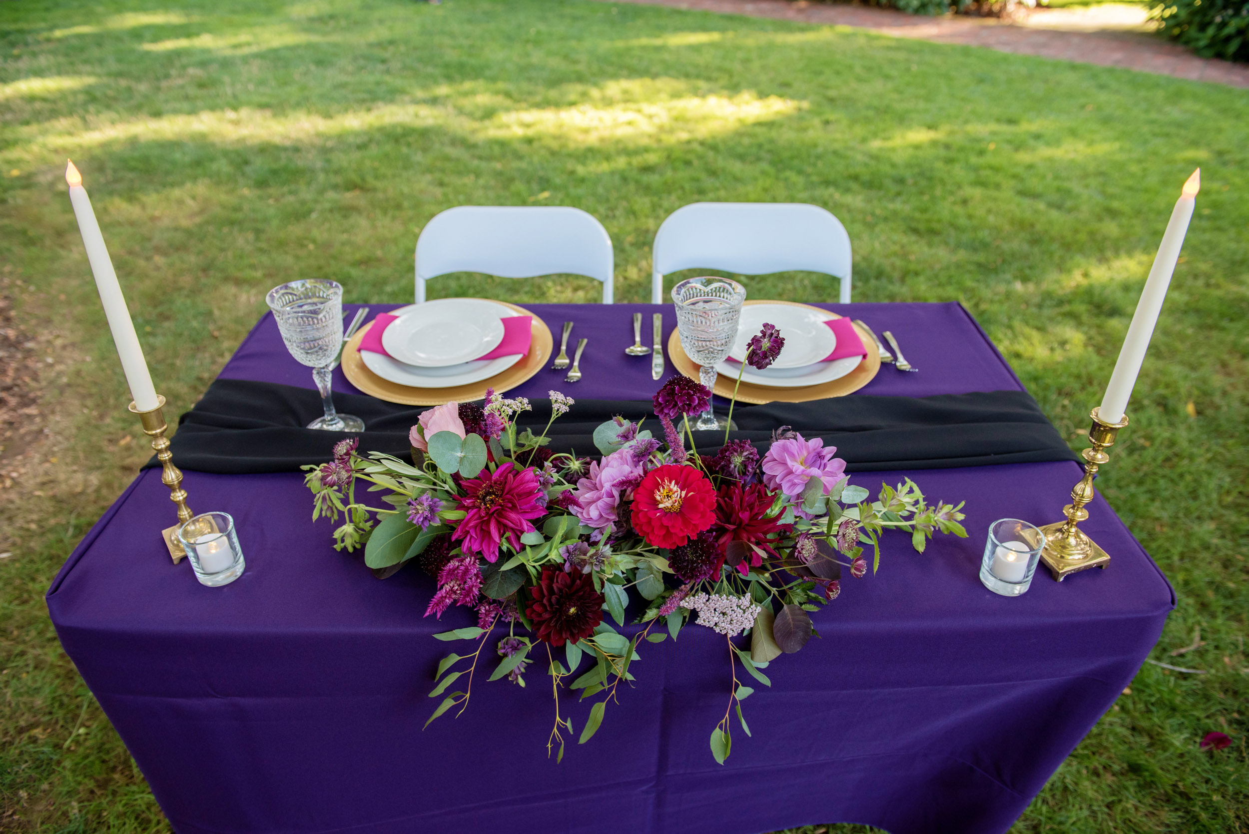 a purple red and pink wedding reception table designed by roses rentals