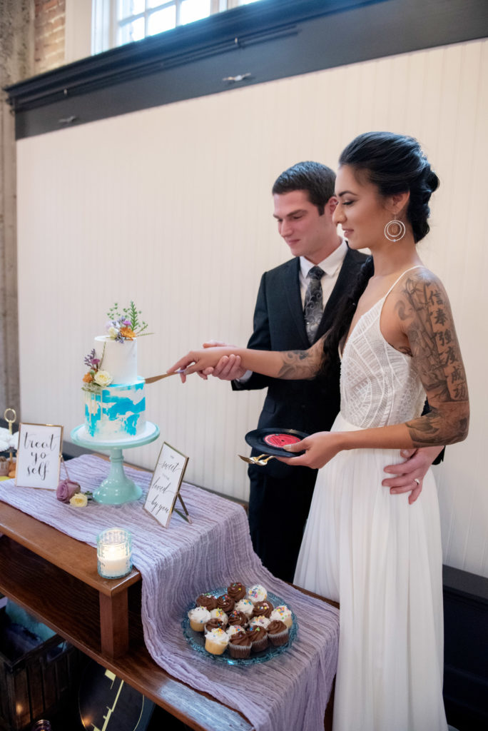 bride and groom cut a pastel watercolor cake and use a vinyl record 7" as a plate