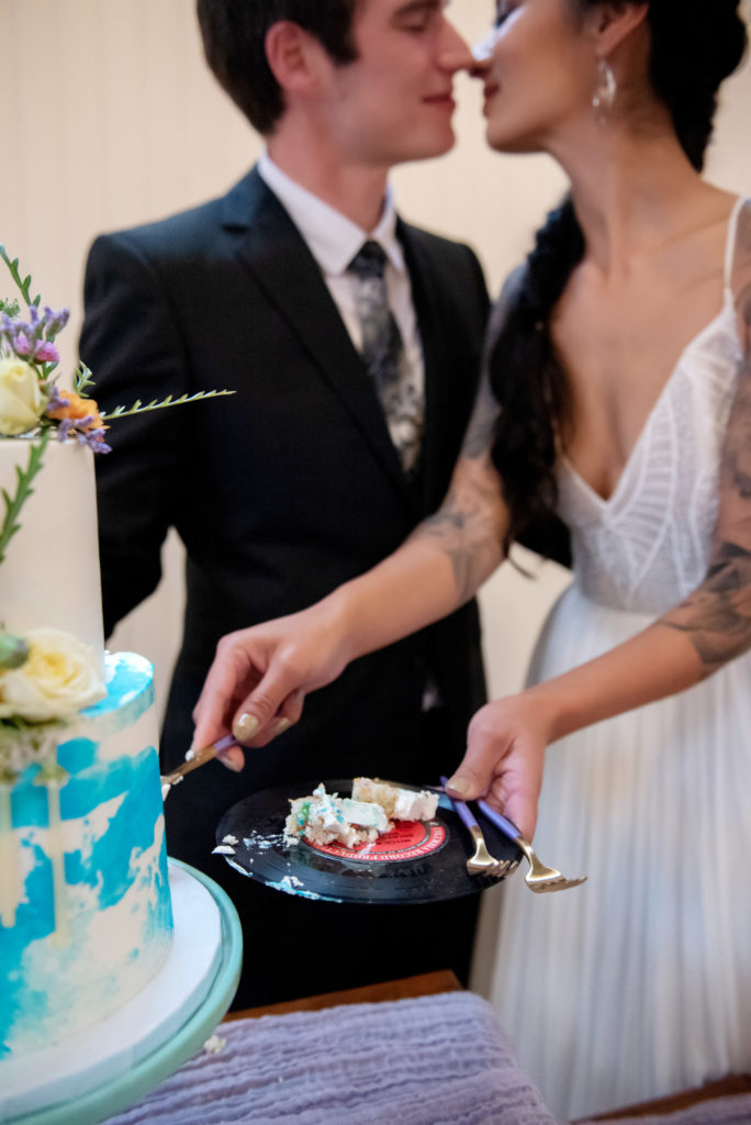 bride and groom cut a pastel watercolor cake and use a vinyl record 7" as a plate