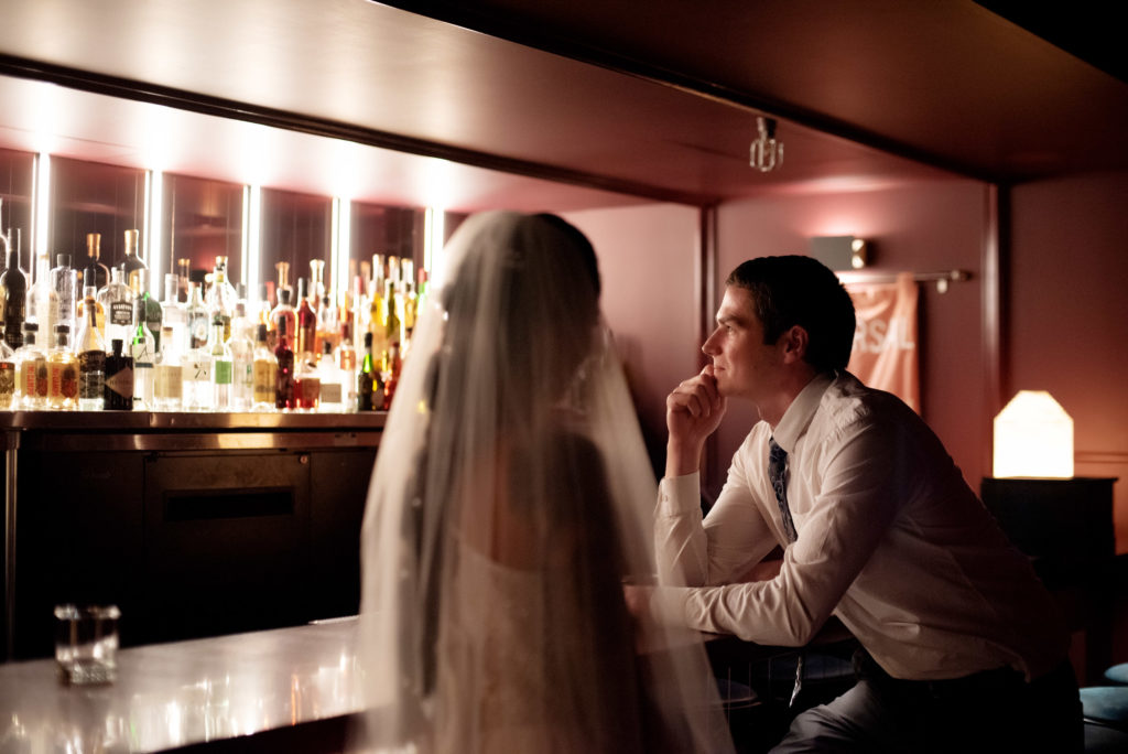 bride and groom sit at the bar at Voysey speakeasy bar
