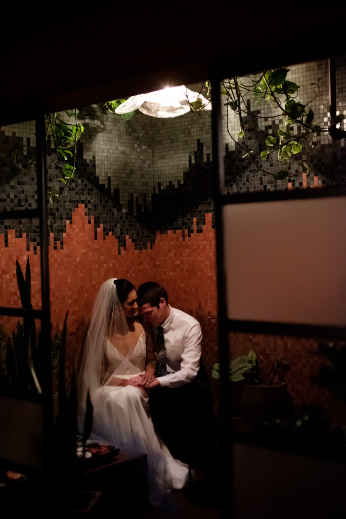 Bride and groom get cozy in the speakeasy Voysey bar under Loyal Legion and the Evergreen