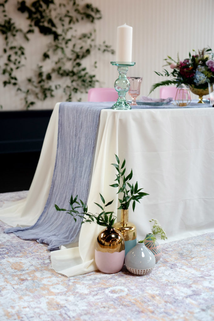 pastel and gold vases with a hand dyed purple cheesecloth runner on a sweetheart table
